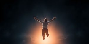 Person reaching for bright light, symbolizing achievement.